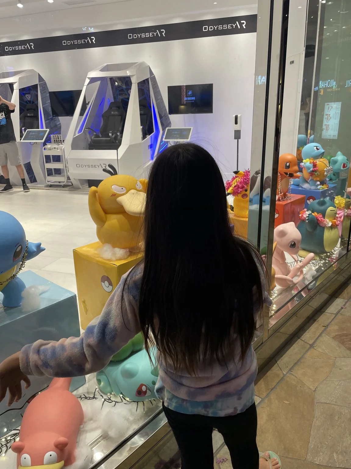 ポケモンの置物が並ぶショーウィンドウを見る子ども