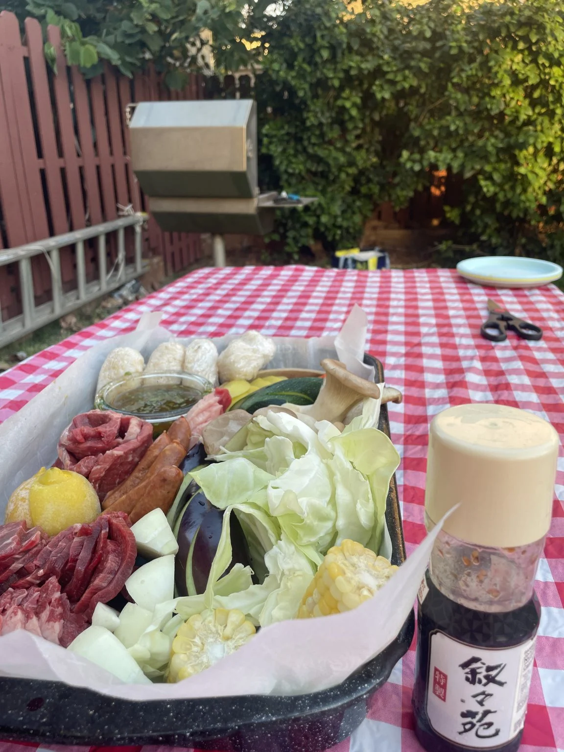 チェック柄のテーブルに並ぶBBQ用の肉と野菜