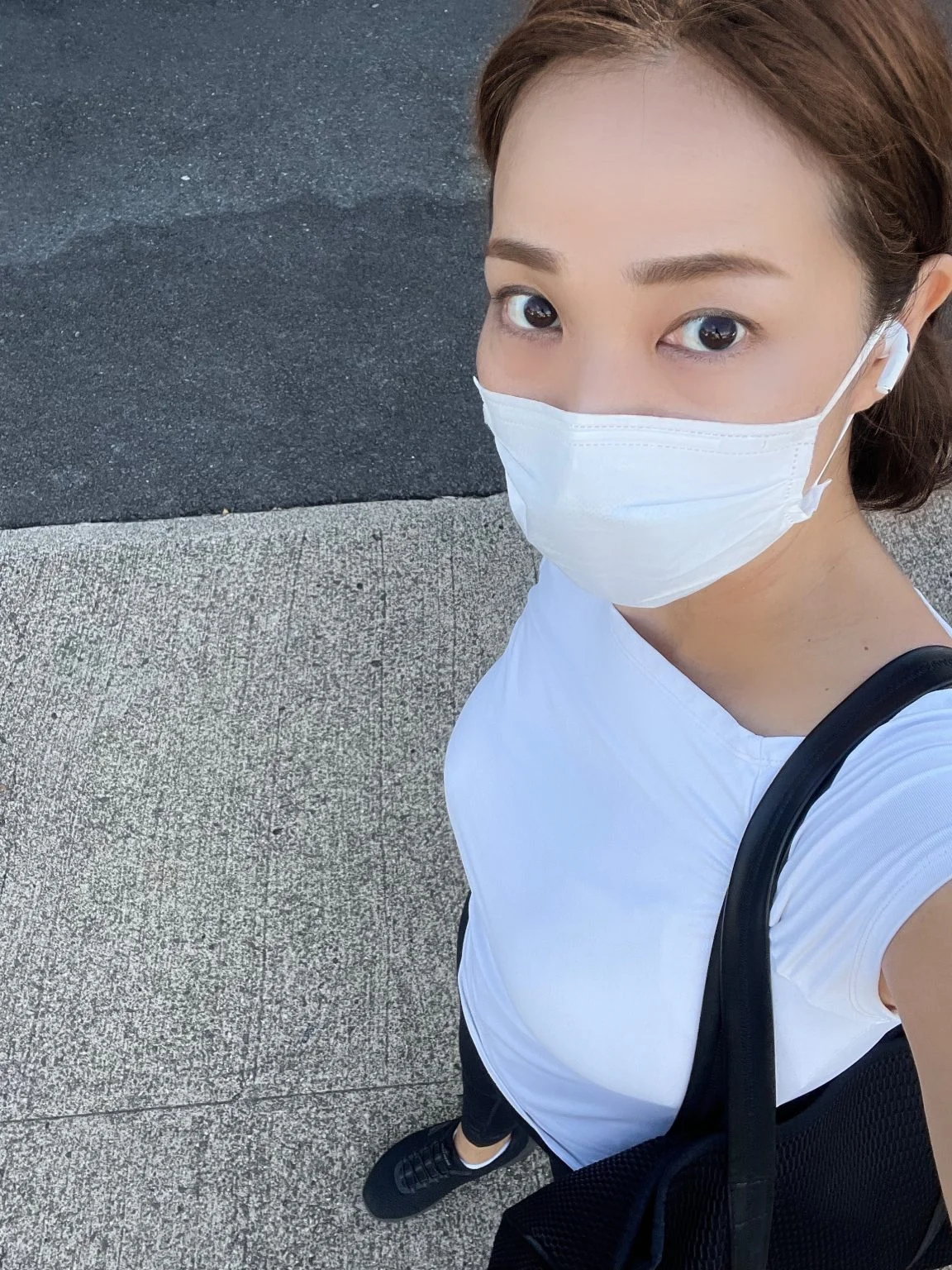 マスク姿で歩く白いTシャツの女性のセルフィー