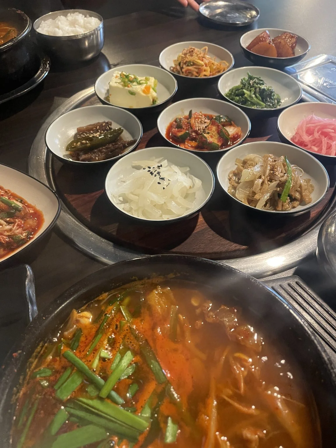 韓国料理店の鍋とずらりと並ぶおかずの小皿