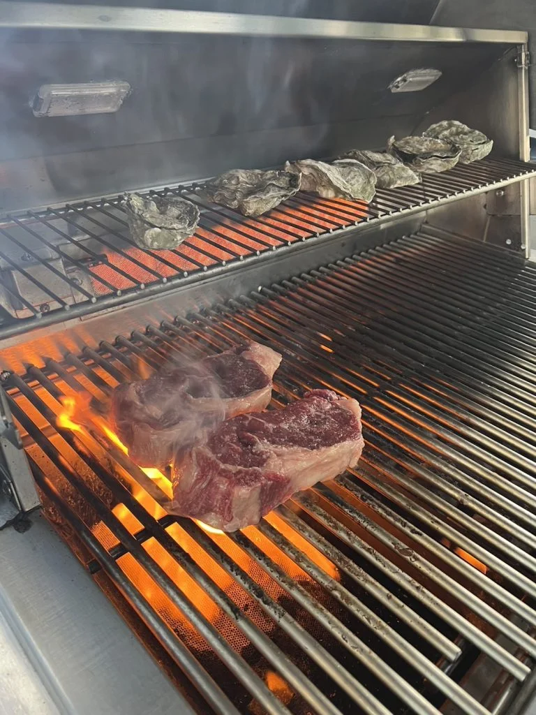 グリルで焼かれるステーキと牡蠣