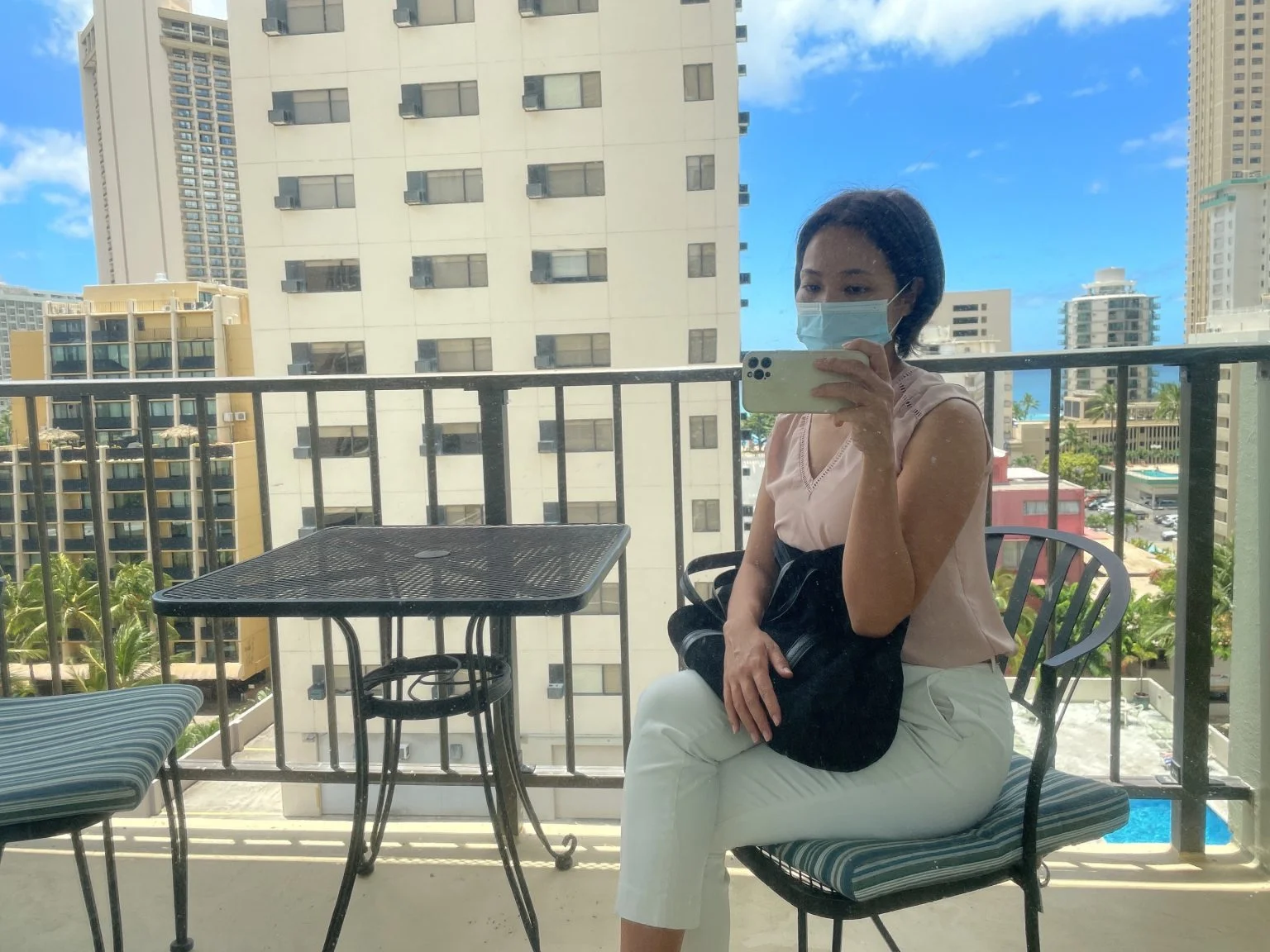 高層ビルが見えるラナイで椅子に座る女性