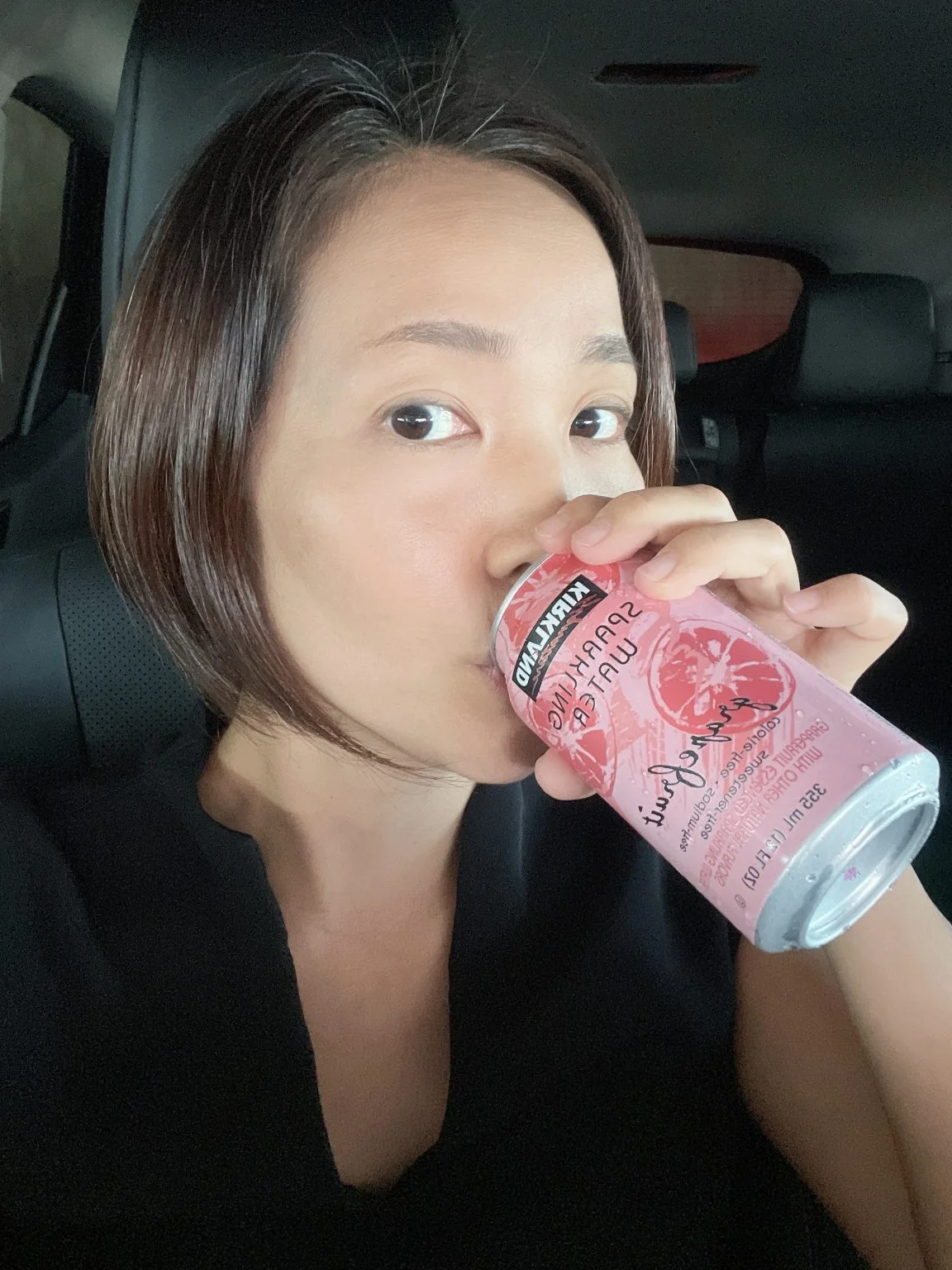 車内で炭酸水の缶を飲む女性