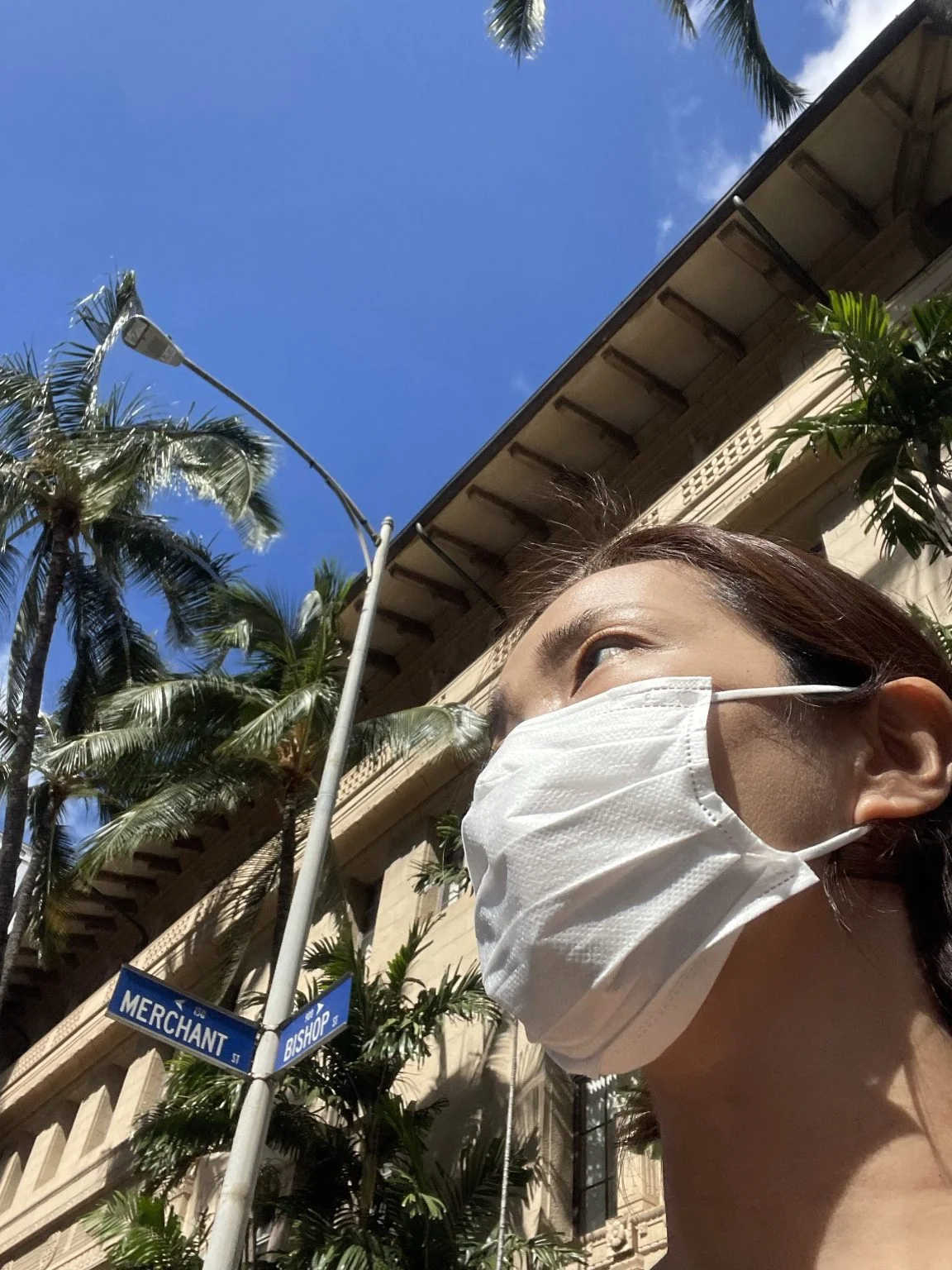 マーチャント通りの標識と歴史的建物の前のマスク姿の女性