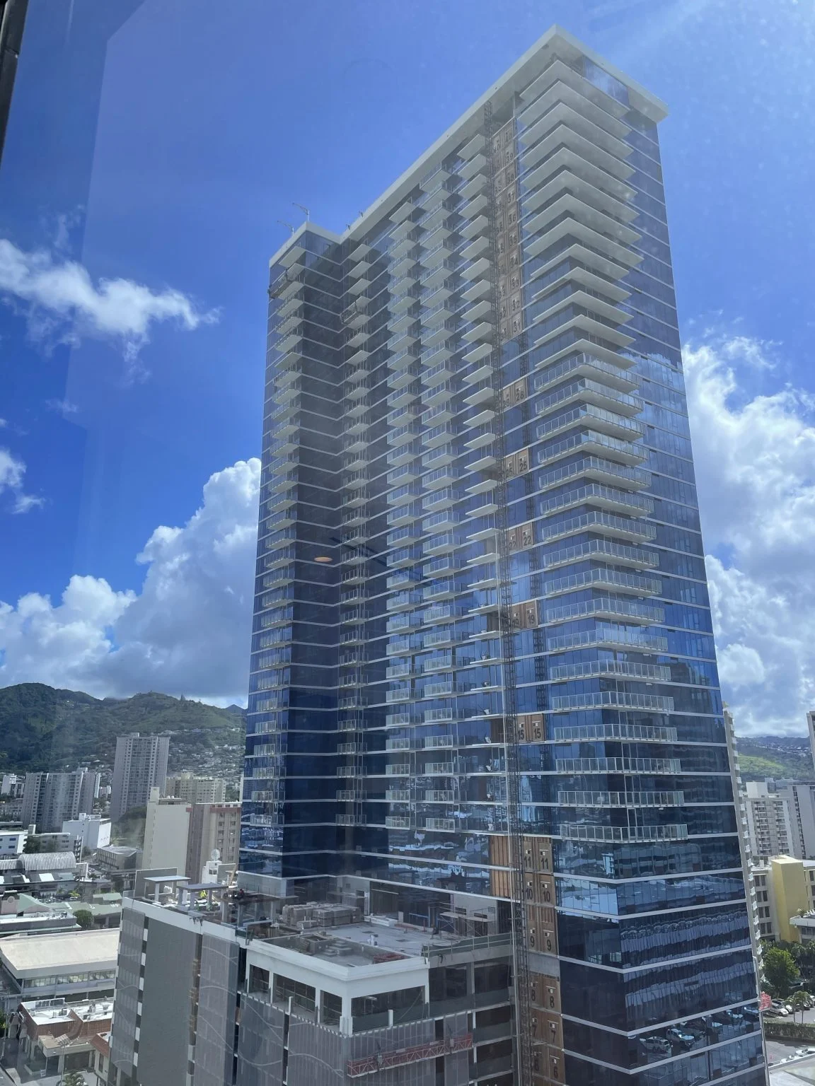 青空にそびえるガラス張りの高層コンドミニアム