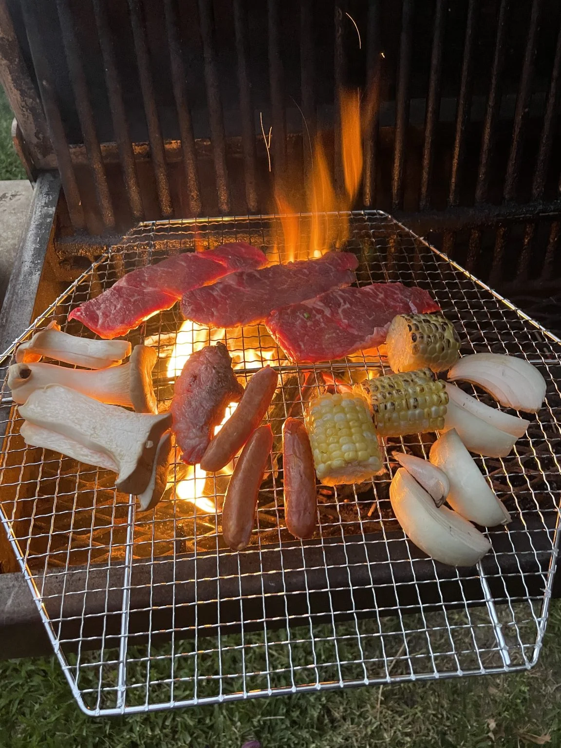 網の上で焼ける肉、ソーセージ、とうもろこし
