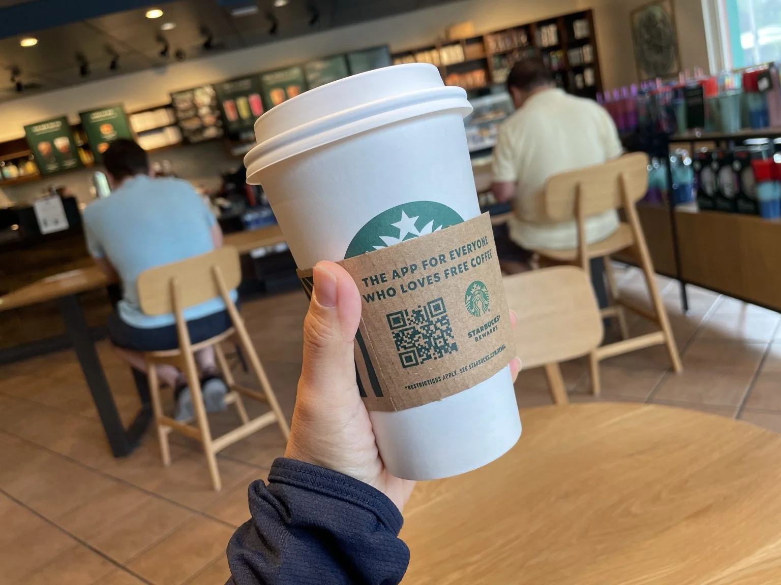 スターバックスのホットコーヒーを手に持つ店内
