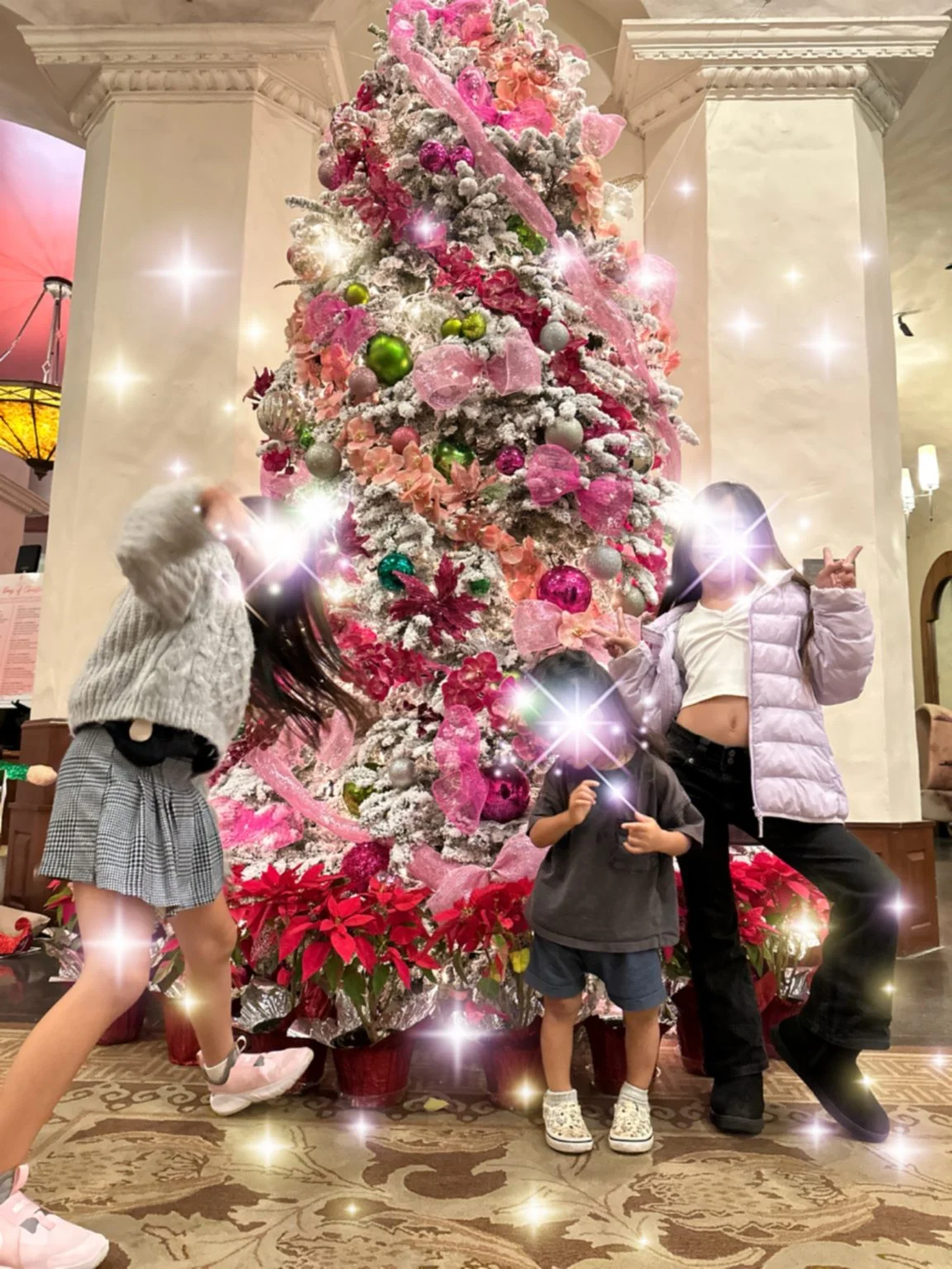 ピンクのクリスマスツリーの前でポーズする家族