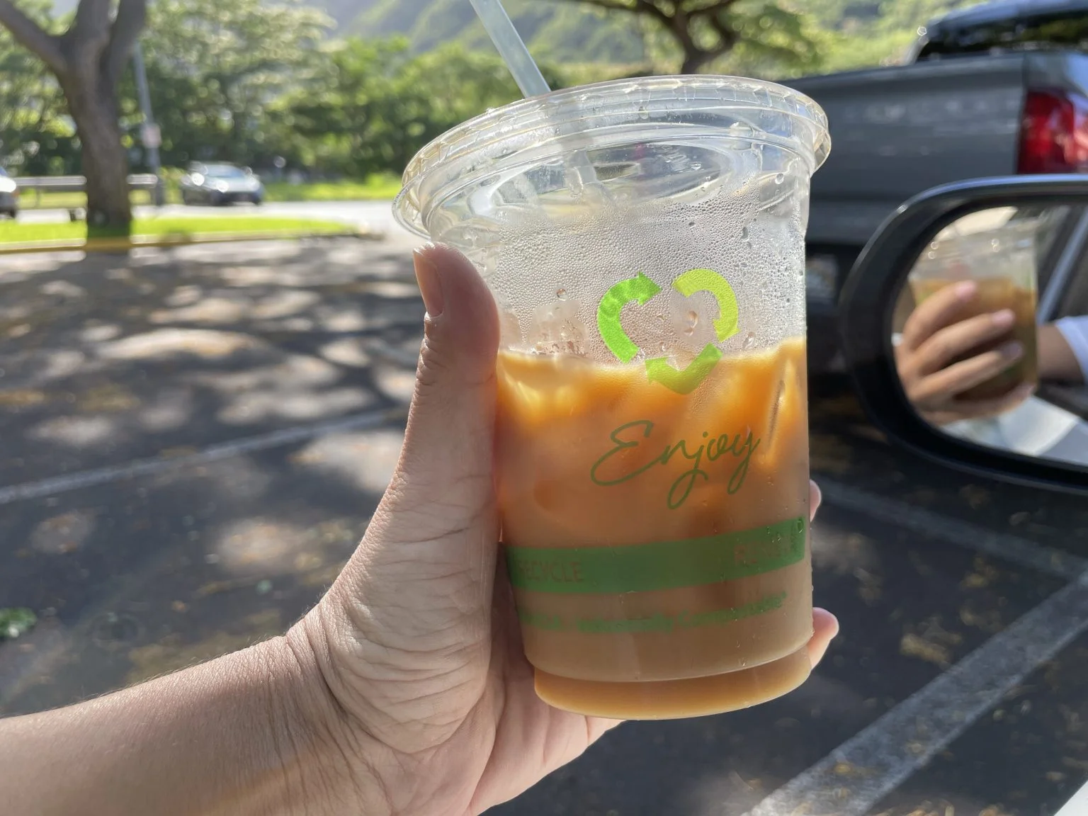 手に持ったアイスコーヒーのカップ