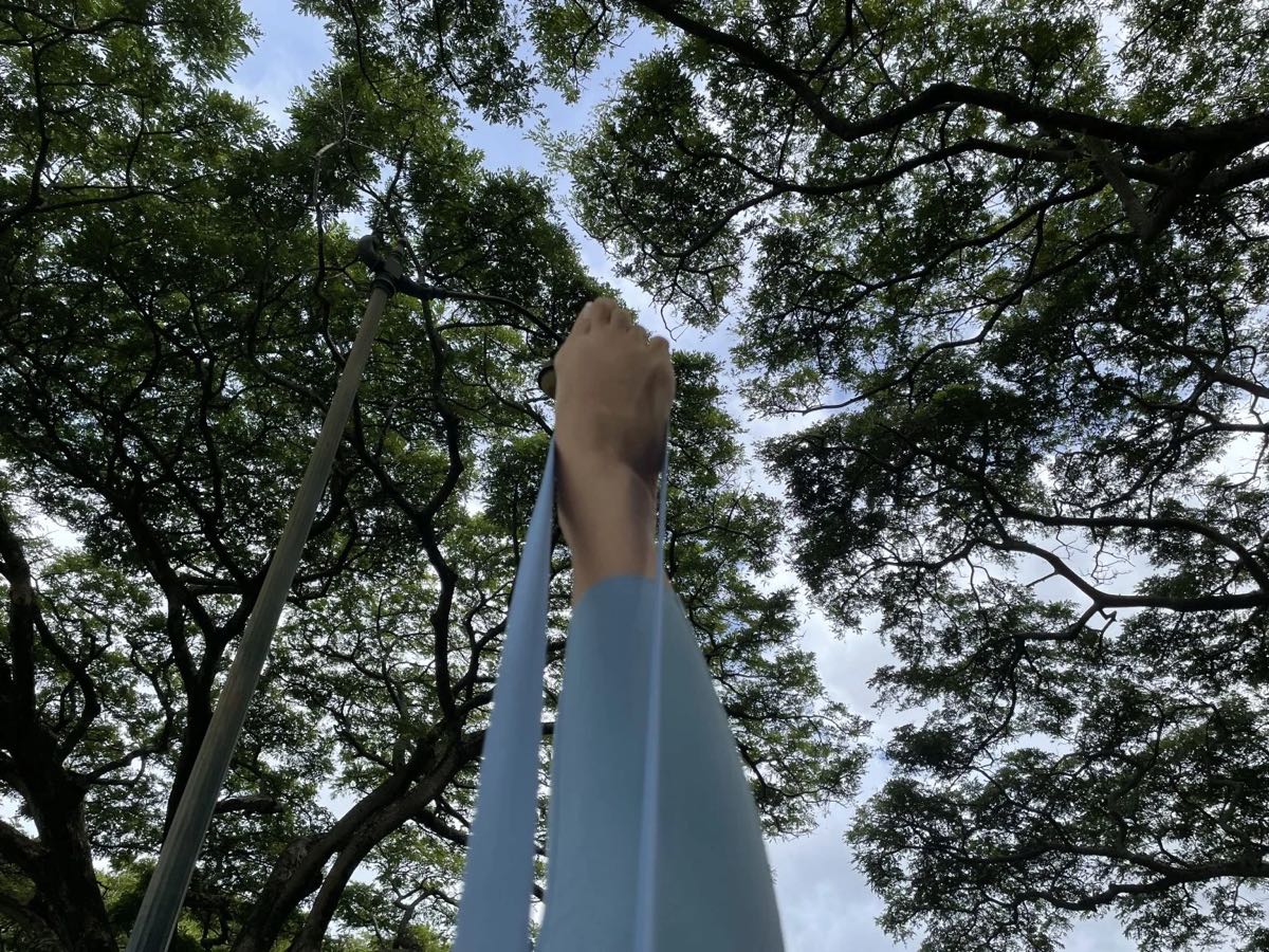 大木の下でバンドを使って脚をストレッチ